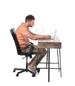 Man with bad posture using laptop while sitting at table on white background�
