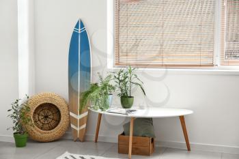 Interior of modern stylish room with surfboard and table with houseplants�