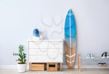 Interior of modern stylish hall with surfboard, shoe stand and chest of drawers�