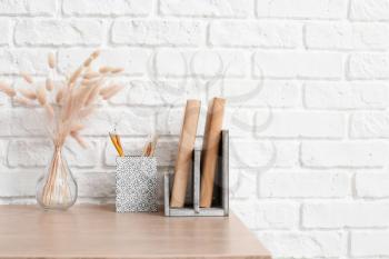 Table with books and organizers near brick wall�