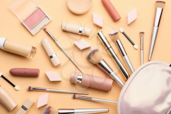 Decorative cosmetics and makeup brushes on color background�