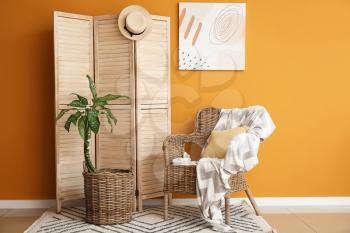 Wooden folding screen and armchair near color wall�