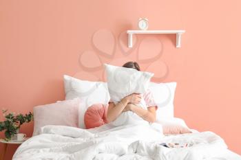 Sleepy young woman hugging pillow in bedroom�
