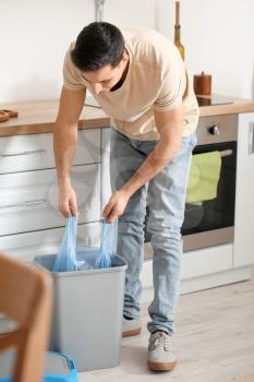 Man taking garbage bag out of trash bin at home�