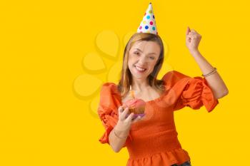 Beautiful woman with birthday cupcake on color background�