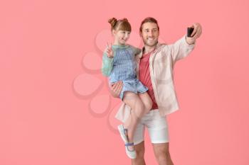 Happy father and daughter taking selfie on color background�