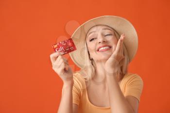 Beautiful young woman with gift card on color background�