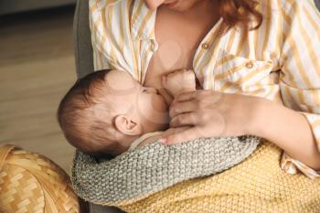 Young woman breastfeeding her baby at home, closeup�