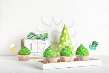 Tasty cupcakes for St. Patrick's Day and calendar on white background�
