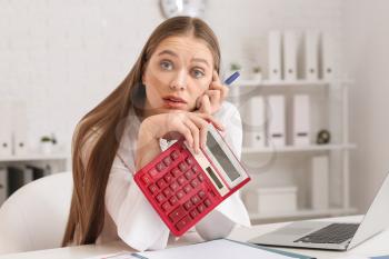 Stressed female accountant with calculator working in office�