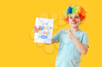 Little boy in funny disguise and with poster on color background. April Fools Day celebration�