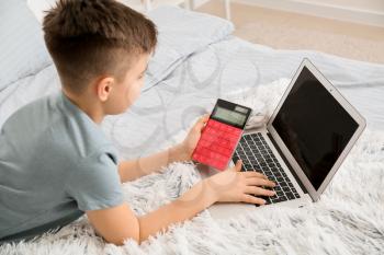 Little boy with laptop and calculator at home�
