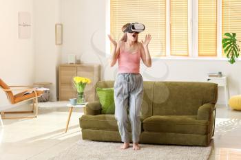 Surprised young woman with virtual reality glasses at home�