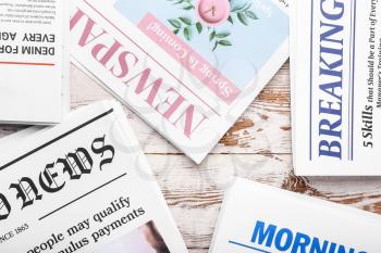 Different newspapers on light wooden background, closeup�