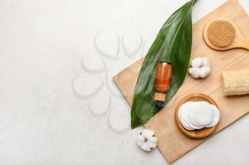 Composition with cotton pads, flowers, brush, sponge and bottle of cosmetic product on light background�