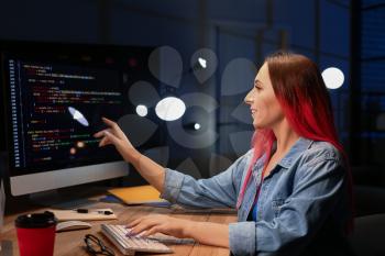 Female programmer working with computer in office at night�