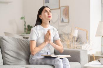 Praying young woman at home�