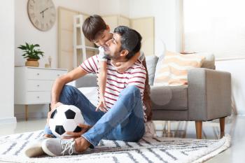 Father and little son with soccer ball at home�