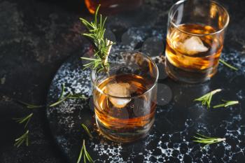 Glasses of cold whiskey on dark background�