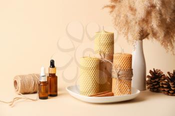 Composition with handmade wax candles and bottles of essential oil on color background�