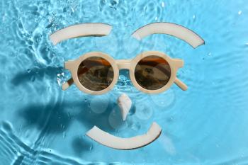 Creative composition with sunglasses, seashell and slices of coconut on color background with water drops�