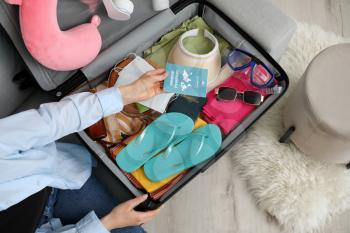 Woman packing suitcase at home�