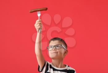 Little boy with tasty sausage on color background�