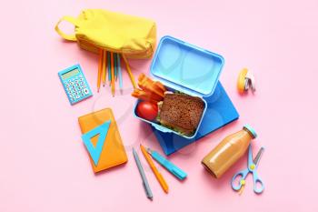 Lunch box with tasty food and school stationery on color background�