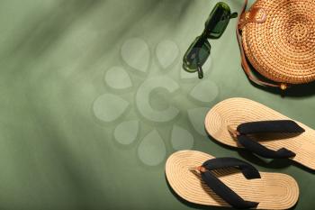 Flip-flops, sunglasses and bag on color background�