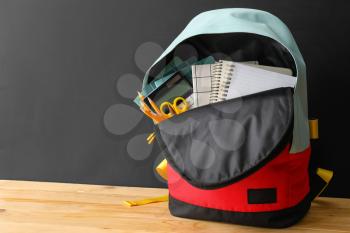 School backpack and stationery on table near blackboard�