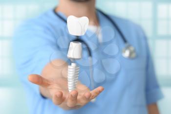 Male dentist with digital model of tooth implant in clinic, closeup�