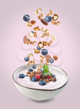 Bowl with tasty yogurt, granola, nuts and berries on color background�