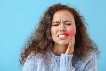 African-American woman suffering from tooth ache on color background�