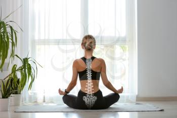 Young woman with good posture meditating at home, back view�