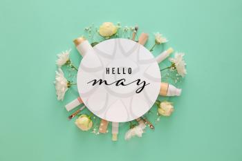 Composition with cosmetics, spring flowers and card with text HELLO MAY on color background�
