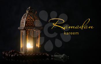 Muslim lamp and tasbih on dark background. Celebration of Ramadan�