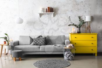 Trendy interior of living room with grey sofa and yellow commode�