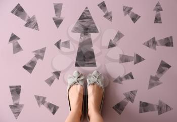 Woman standing on color background with arrows pointing in different directions. Concept of choice�