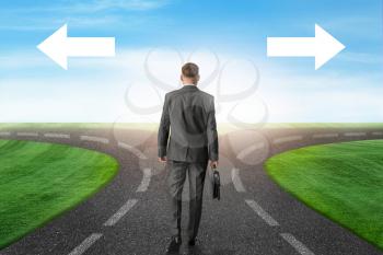 Businessman standing at crossroads with arrows. Concept of choice�