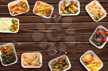 Containers with delicious food on wooden table. Delivery service�