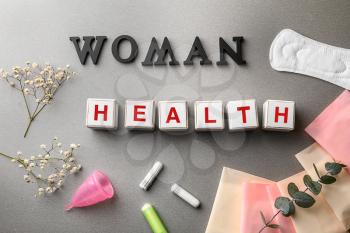 Cubes composed words WOMAN and HEALTH on grey table�