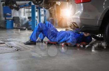 Male mechanic fixing car in service center�
