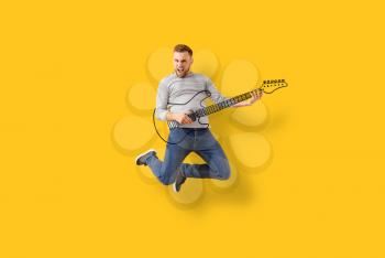 Jumping young man with drawn guitar on color background�