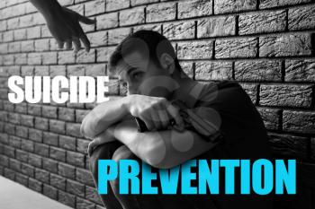 Woman giving hand to depressed man with gun near dark wall. Suicide prevention concept�