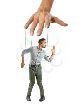 Hand of puppeteer manipulating man as marionette on white background�