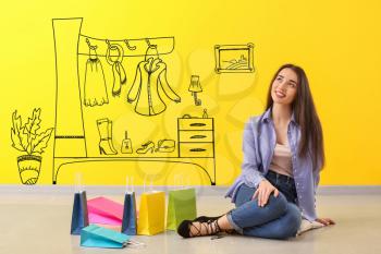 Thoughtful young woman with shopping bags imagining interior of dressing room�
