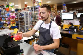 Male cashier checking out goods in supermarket�