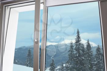 View on beautiful snowy forest through big metal-plastic window�