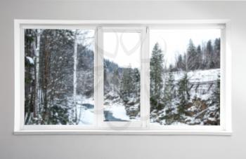 View on beautiful snowy forest through big metal-plastic window�
