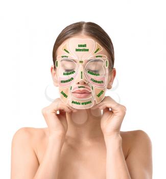 Beautiful woman with reflexology massage chart on her face against white background�